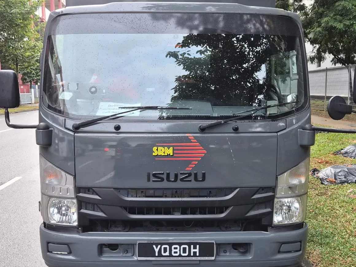 Isuzu box lorry in SRM Logistics livery photographed head-on at the kerb, the SRM mark above the Isuzu badge on the cab front